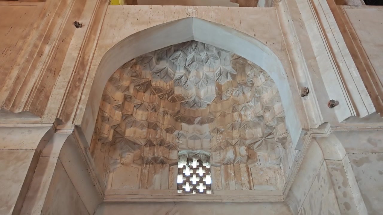Vista interna di architettura antica in pietra con finestra a grata intricata