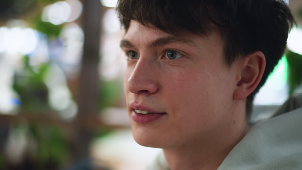 student in white shirt listening to friend while folding eyebrow in curiosity, showing attentive expression and subtle skepticism, indoor casual setting conveying thoughtful interaction