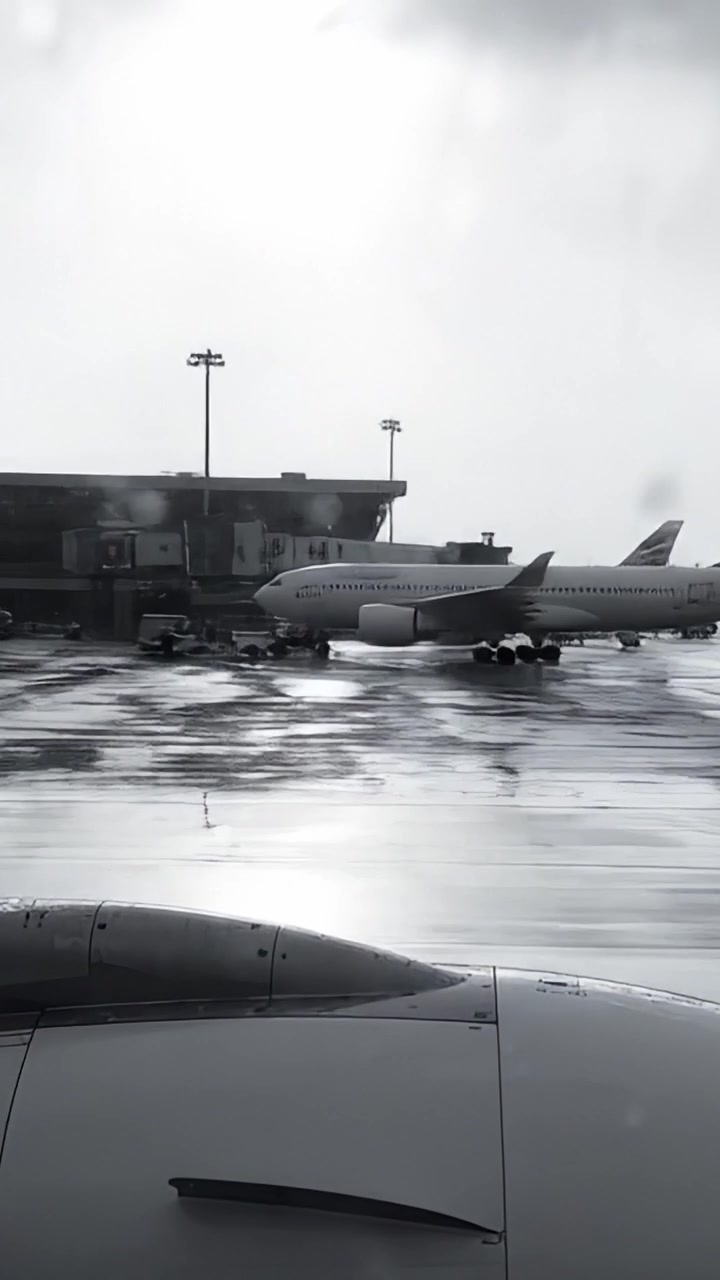 Vista Atmosférica de Aviões no Pátio de Manobras de um Aeroporto Durante um Dia Chuvoso, Exibindo as Sombras e Reflexos de Aeronaves e Equipamentos de Solo