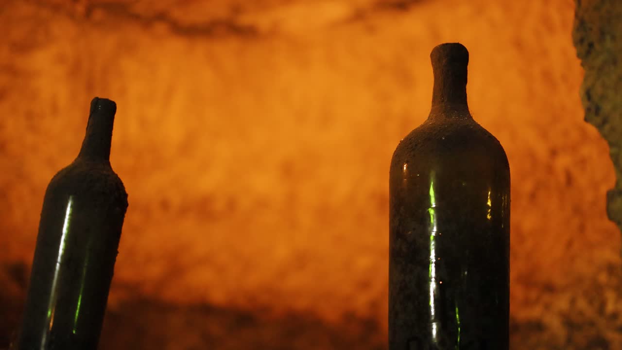 duas garrafas de vinho numa adega mal iluminada