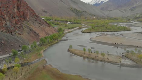 aerial over riverbend of ghizer river with valley landscape in the background in pakistan