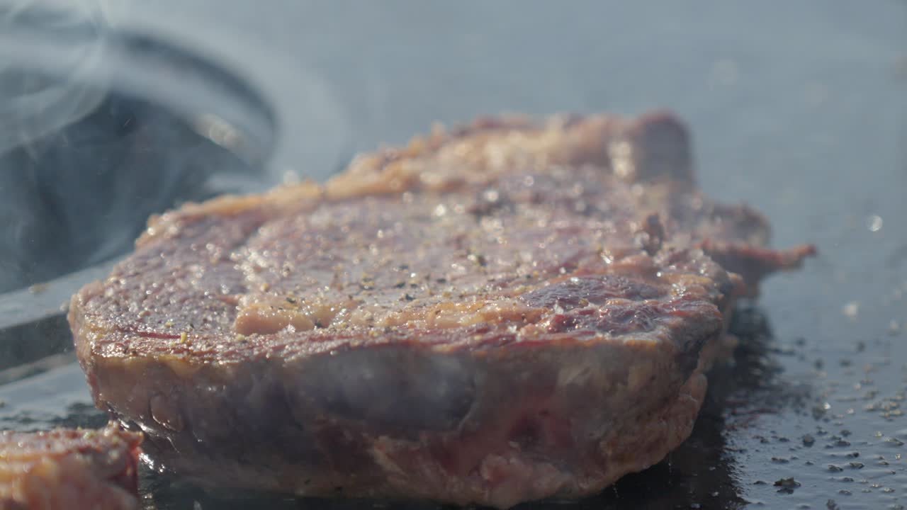 Metal grates over a fire pit with logs burning and smoking