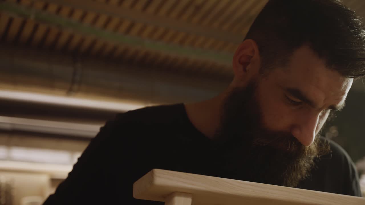Focused craftsman assembling a wooden chair frame using clamps in a woodworking workshop, symbolizing precision, handmade furniture craftsmanship, and attention to detail