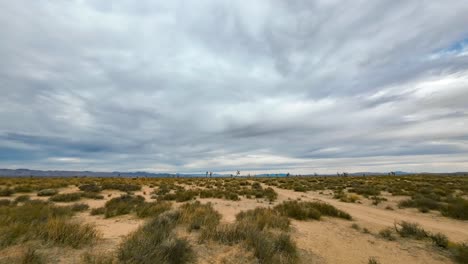 an overcast sky in the mojave desert flows towards the mountains in this daytime, wide angle time lapse with joshua trees and mountains in the background