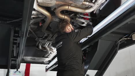 Mecánico-De-Garaje-Examinando-Debajo-Del-Coche-En-El-Taller-De-Reparación.