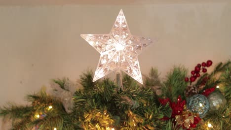 star decoration with flashing led lights on top of christmas tree