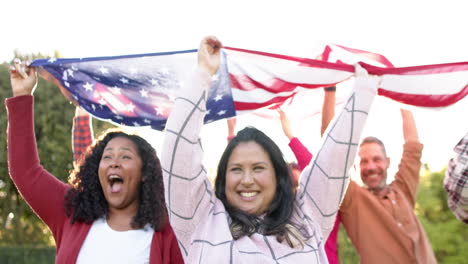 Happy-diverse-male-and-female-friends-dancing-with-flags-in-sunny-garden