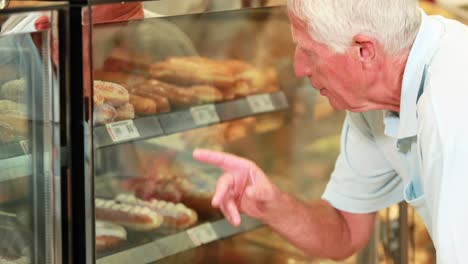 senior man picking a cake in supermarket