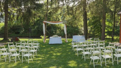 pan shot of wedding ceremony with an arch and chairs during the day in the forest, wide shot