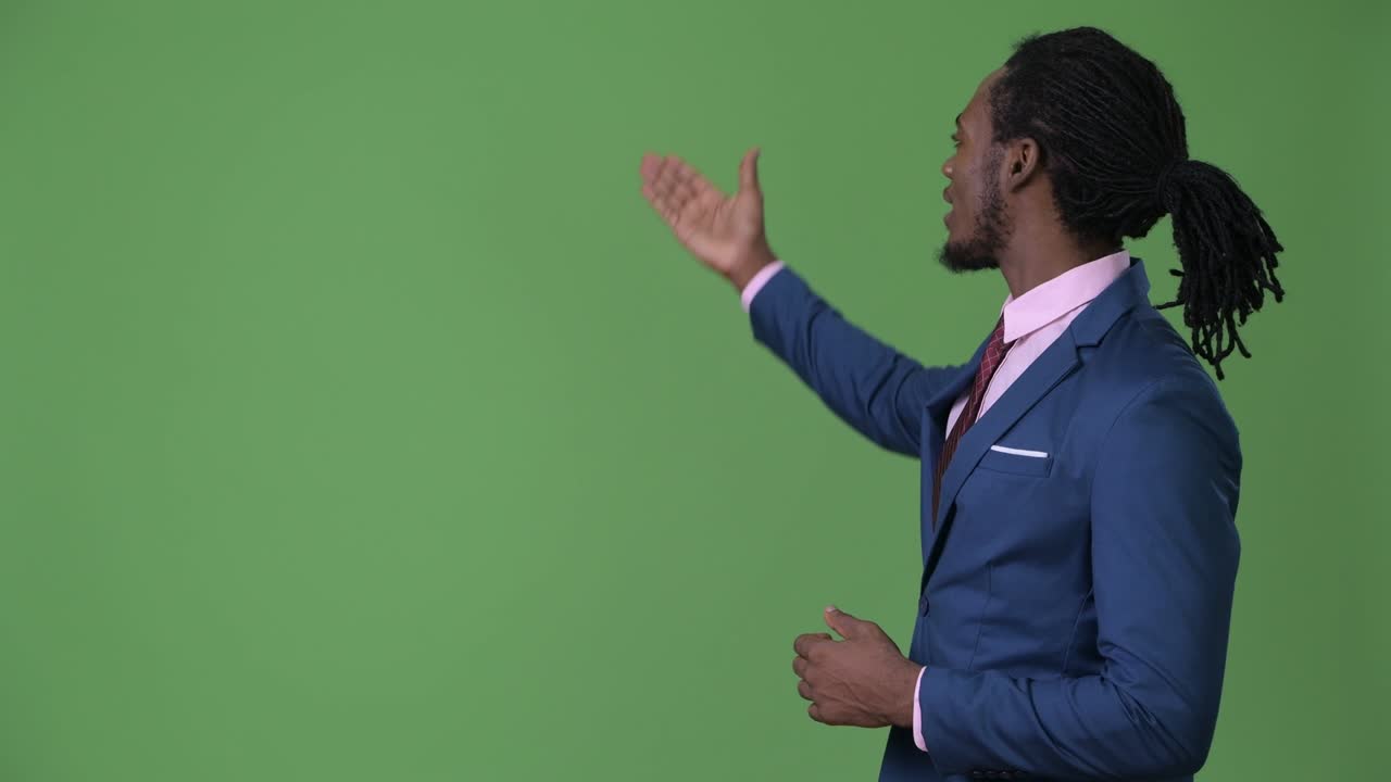Young handsome African businessman with dreadlocks against green background