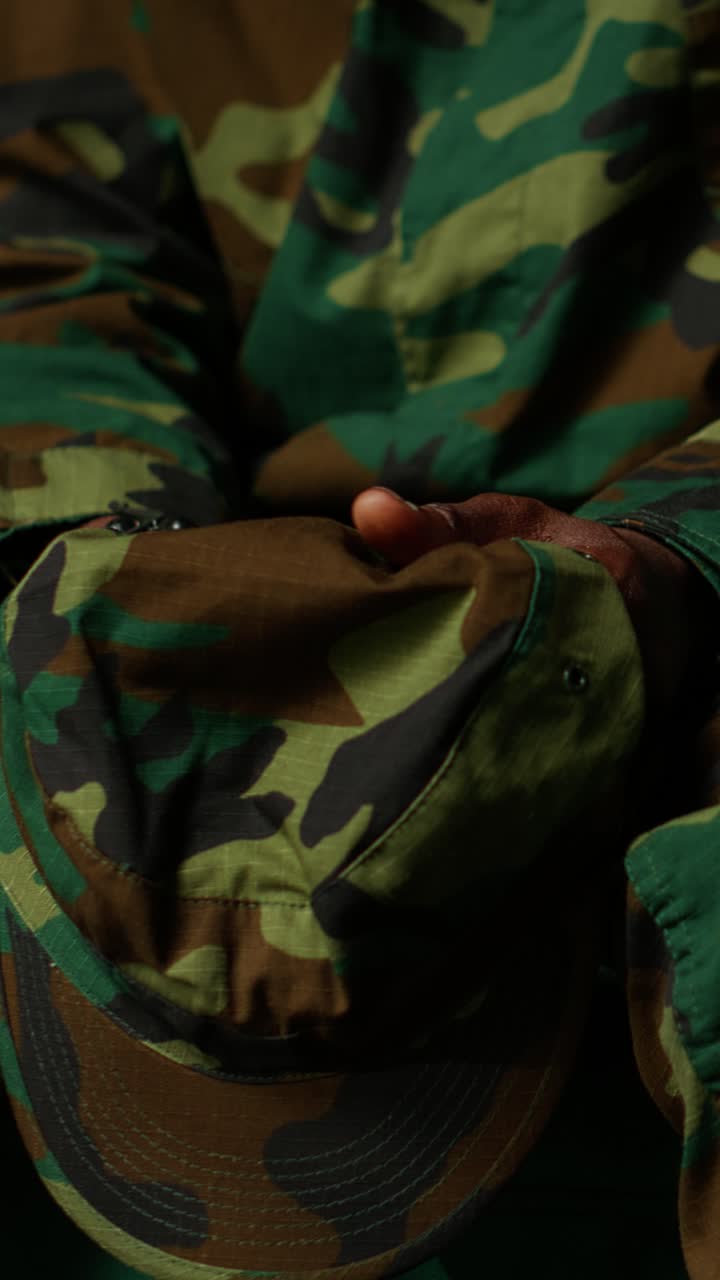 Primo piano di una mano che sistema un cappello militare mimetico