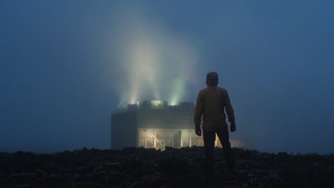 iceland, blue lagoon, svartsengi geothermal power station at night, silhouette of a one person walking towards the factory, medium wide shot