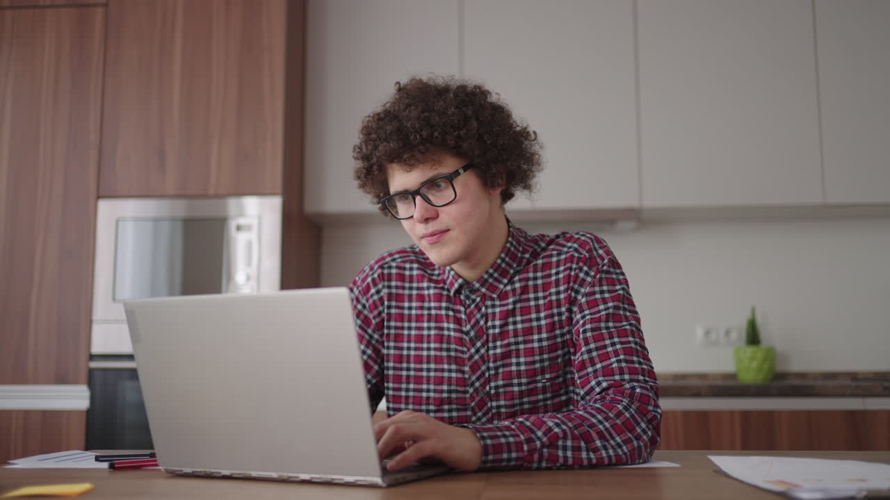joven con un teléfono inteligente en sus manos. hombre de negocios moderno o estudiante en la oficina de casa. profesional independiente en el trabajo. joven estudiante estudia en casa con una computadora portátil y usa un teléfono inteligente