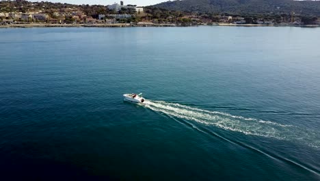 aerial view of a white motorboat sailing on a calm blue sea near the coast