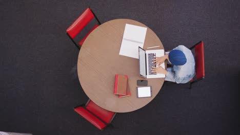 asian female student wearing a blue hijab sitting and using a laptop