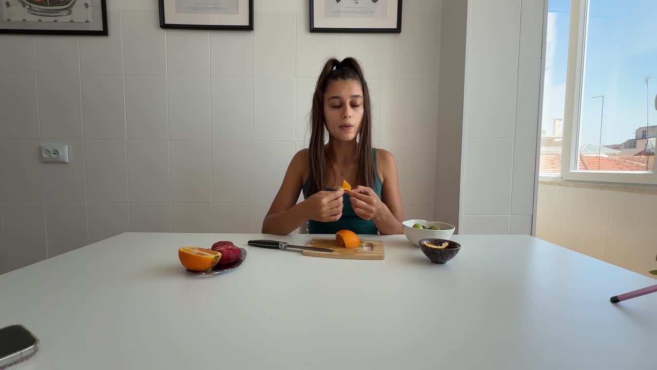 Young Woman Peeling and Eating a Fresh Orange at Home
