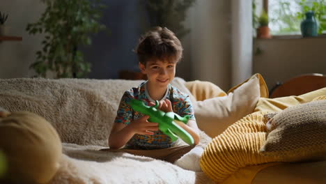 happy boy playing with toy dinosaur on couch