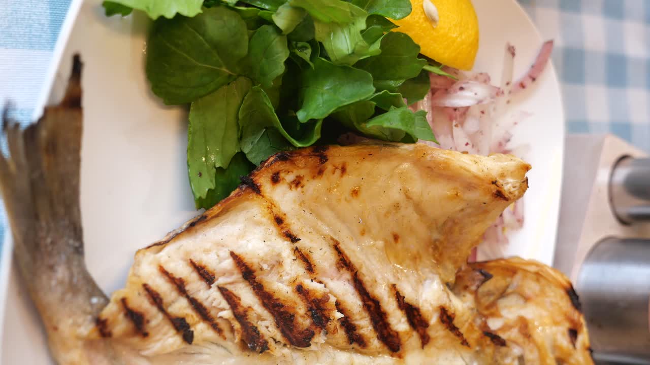 Close-up of Delicious Grilled Fish on a Plate with Greens