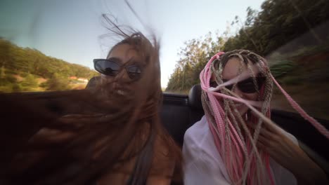 two joyful women enjoying a scenic convertible road trip with wind in their hair