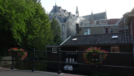 smoke coming out on chimney of a house with sint janskerk church in the background in gouda, netherlands