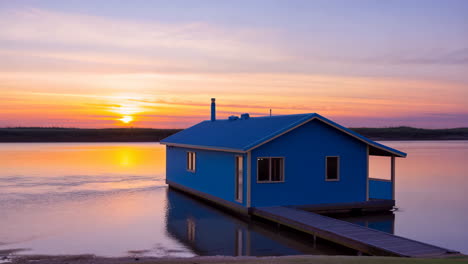 blue house on calm water at sunset