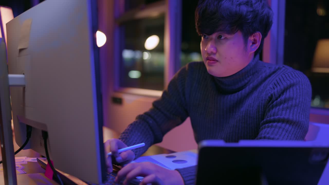 성인 아시아 남성 프리랜서 스웨터를 입고 늦은 밤 집에서 일하는 아시아 남성 젊은 성인 집에서 공부하는 방에서 혼자 옷 옷 셔츠를 입고 데스크 pc 앞에서 일합니다.