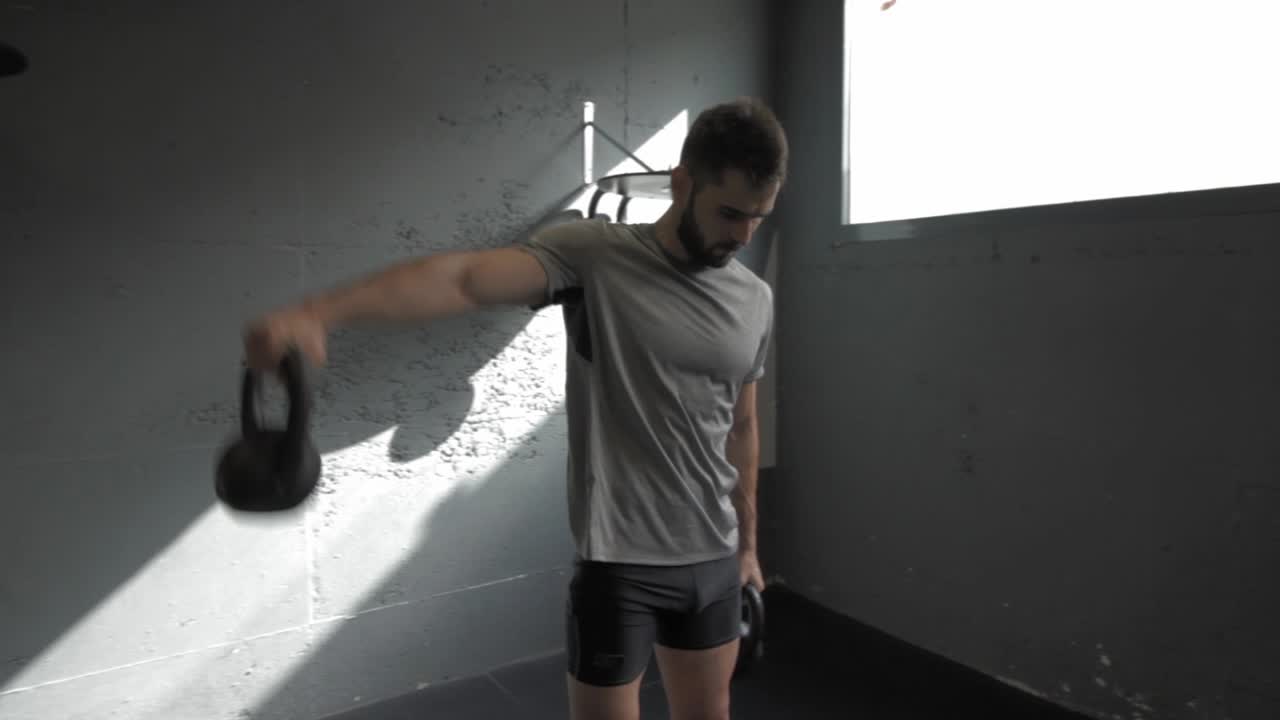 케틀벨을 들고 체육관에서 운동을 하는 젊은 운동선수