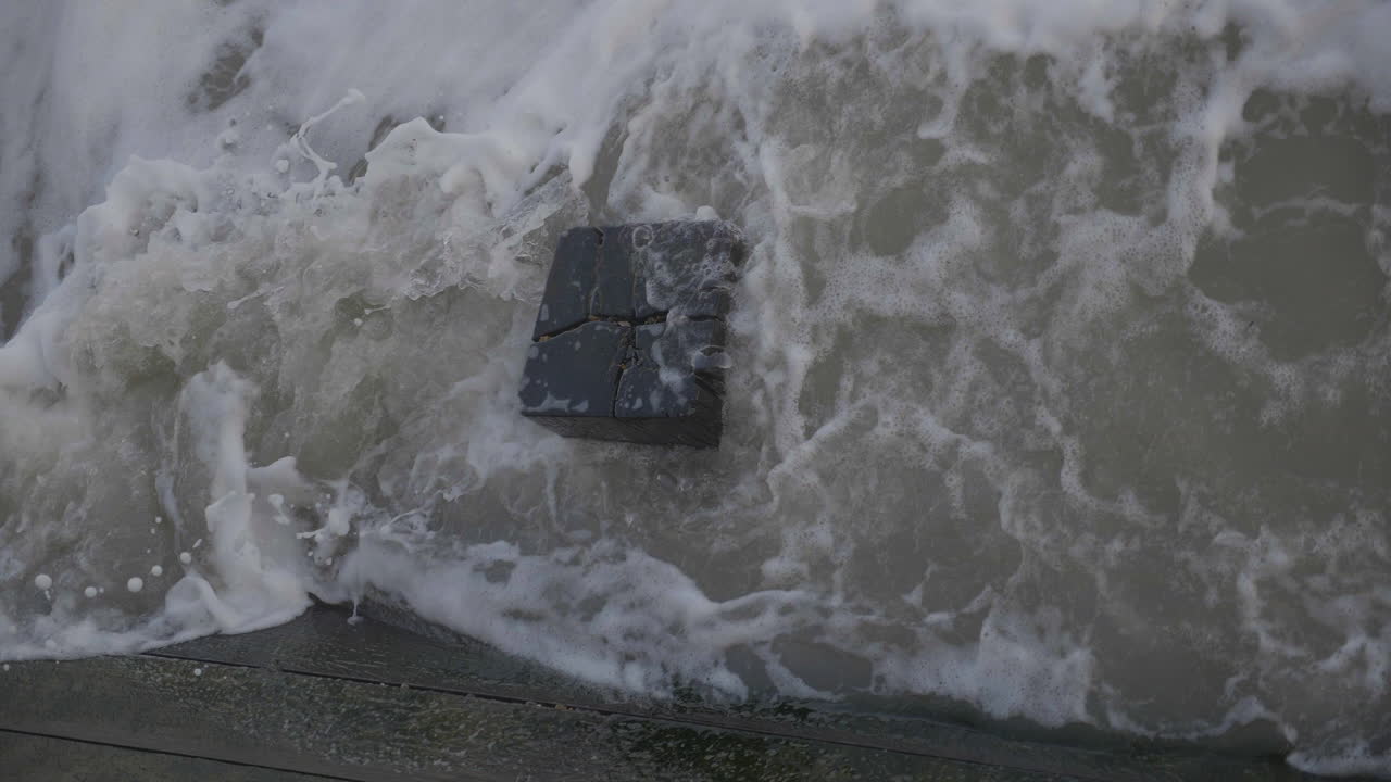 The sea smashing up against a wooden pier pylon