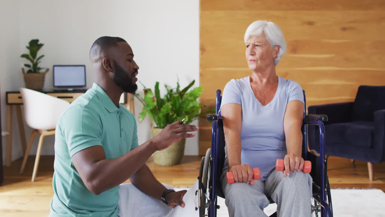 Video of african american male physiotherapist exercising with caucasian senior woman