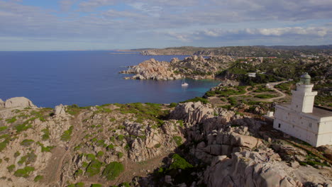 vista aérea pasando por el faro de cabo testa en la isla de cerdeña y viendo la majestuosidad del paisaje costero