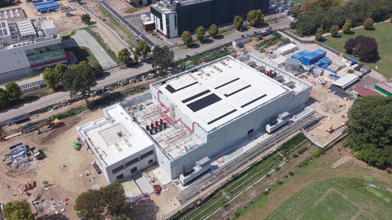 Vista aérea del Centro de Datos MIL03 en construcción en Castelletto, Lombardía, mostrando un techo blanco, paneles solares y equipo de refrigeración dentro de una obra activa