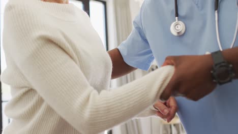 video de la sección media de un médico afroamericano que cuida a una mujer caucásica mayor