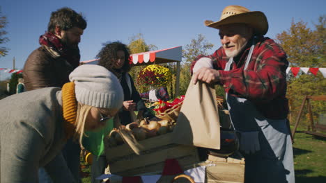 people shopping at local farmers market people shopping choosing fruits and vegetables at local farmers market packing goods in eco bags autumn fair on weekend outdoors vegetarian and organic food agriculture points of sale system