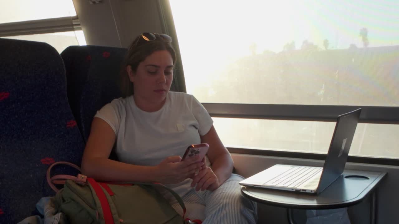 Woman Using Her Smartphone on a Train as Evening Approaches