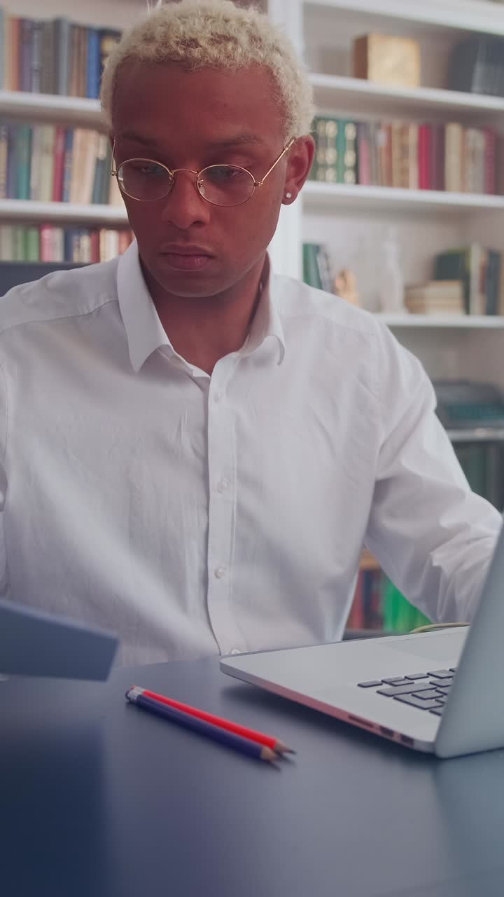 Young african american man working diligently at a laptop in a cozy office