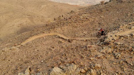 Adult-male-mountain-biker-riding-downhill-enduro-off-road-with-full-face-helmet-protection-during-dusk-in-Showka,-Shawka,-Ras-Al-Khaimah,-UAE