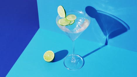 close up of transparent drink with lime on blue background