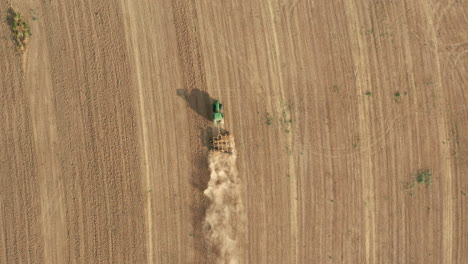 agricultural tractor tilling - plowing the farm land - overhead aerial drone view