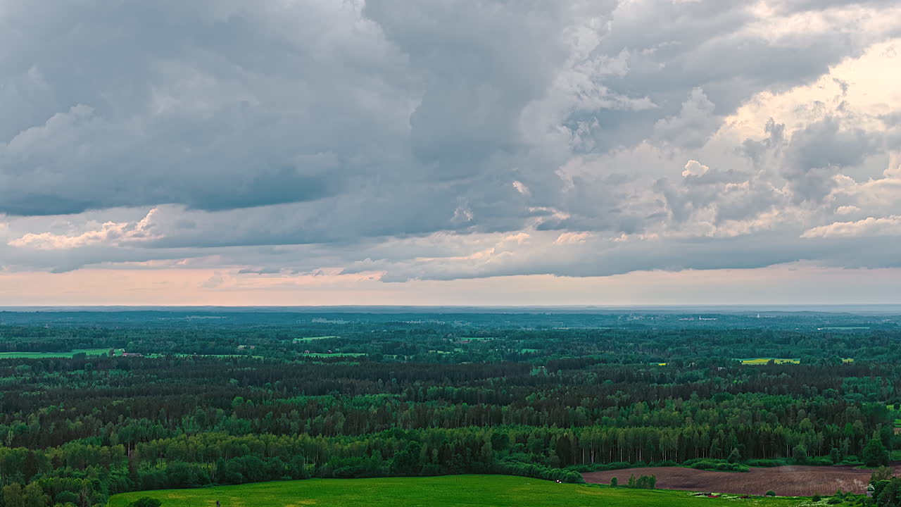 Cloudy sky stretches above vast green plains and fields, rural backdrop with soft horizon