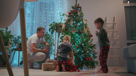 A-family-with-two-children-decorate-a-Christmas-tree-on-Christmas-Eve.-Father-and-mother-with-children-prepare-for-new-year-and-Christmas-decorating-house.-High-quality-4k-footage