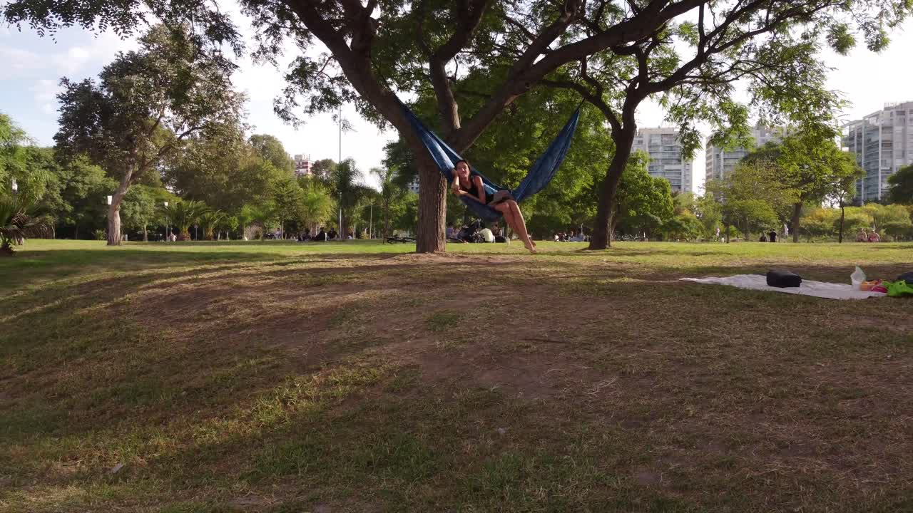 niña relajándose en una hamaca en un hermoso parque y hablando por teléfono