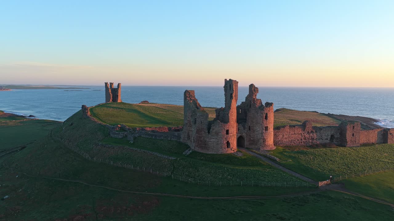 Gylden solopgang over ruinerne af Dunstanburgh Castle.