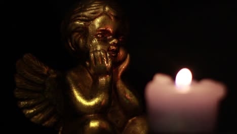 estatuilla de ángel mirando la vela en la oscuridad