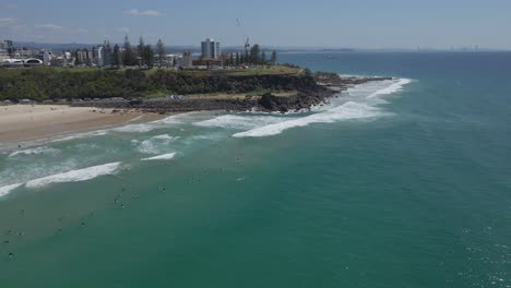 Vista-Panorámica-De-Los-Surfistas-En-La-Playa-De-Duranbah-Con-Punto-De-Observación-De-Peligro-En-El-Telón-De-Fondo-En-La-Costa-De-Oro,-Australia