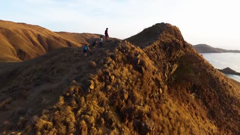 komodo national park aerial view of group of trekkers hiking the gili lawa darat mountain island crest rock cliff formation for the sunrise over the ocean