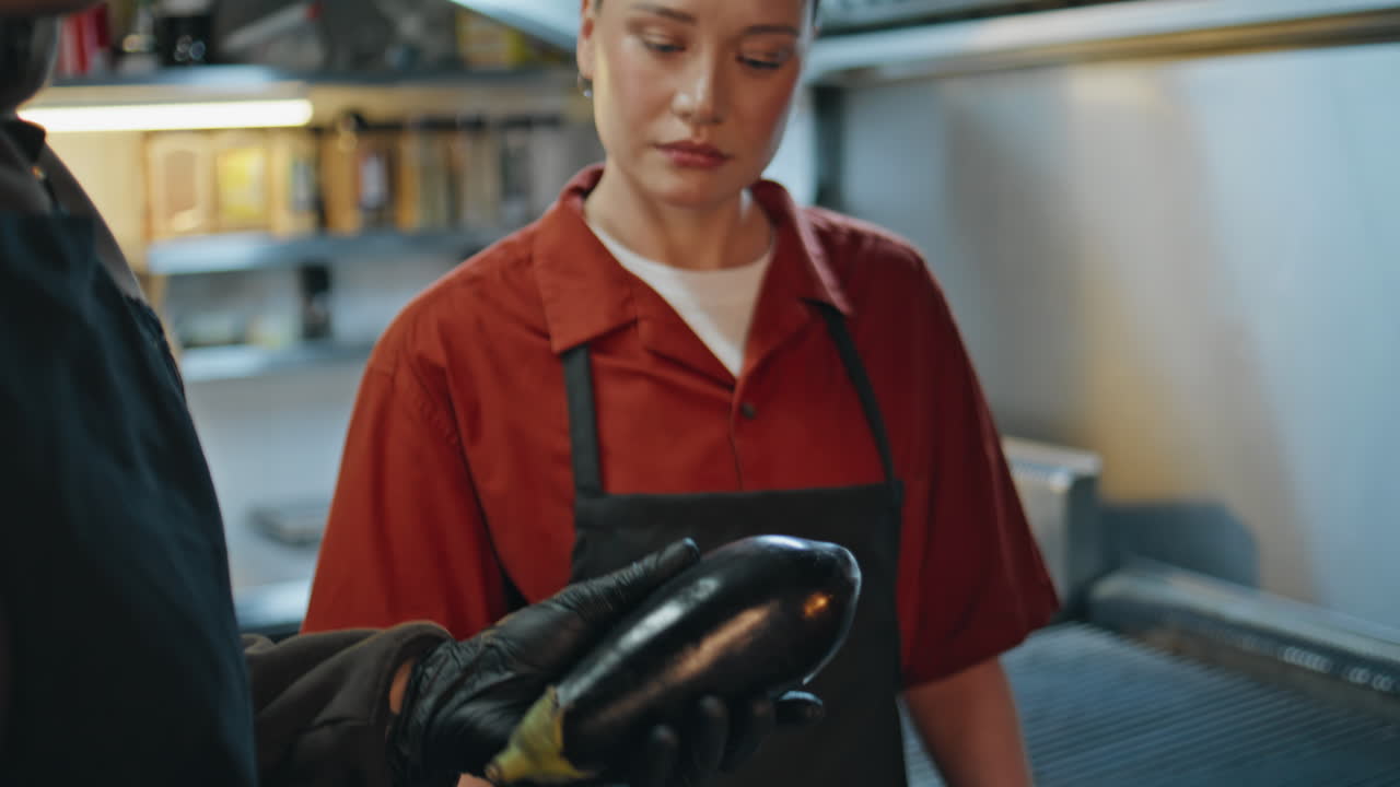 Chef preparing fresh eggplant in professional kitchen closeup. Female listening