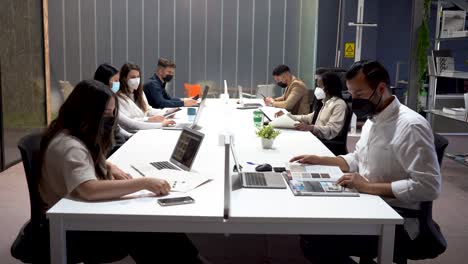 Group-of-colleagues-sitting-at-table-in-office-and-working