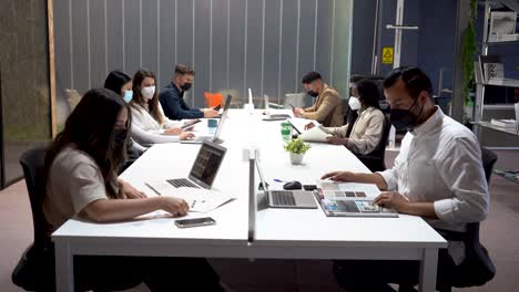 group of colleagues sitting at table in office and working