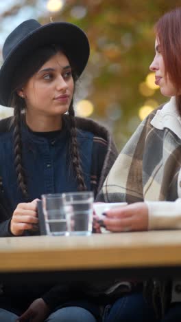 two friends enjoying coffee outdoors in autumn