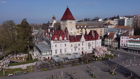 Slow-aerial-orbit-shot-above-a-large-hotel-built-on-the-site-of-an-old-medieval-castle-in-Lausanne,-Switzerland-on-a-sunny-day